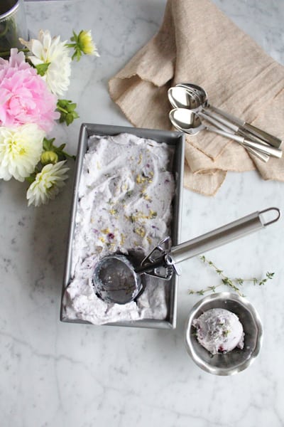 A pan of Blueberry Lemon and Thyme Ice Cream with a scoop of ice cream in a dish.