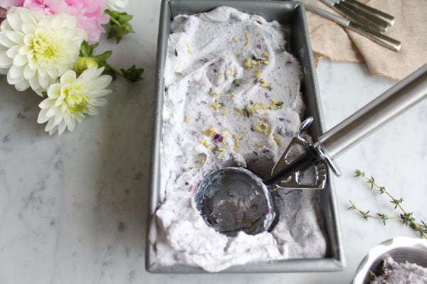 Blueberry Lemon and Thyme Ice Cream in a pan with a scoop.