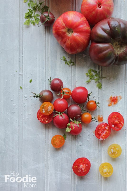 Heirloom tomatoes on a white wood surface.