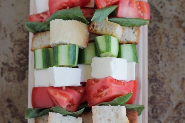 Caprese kabobs on a wood cutting board.