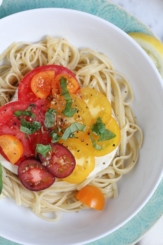 Summer Caprese pasta salad in a white bowl.