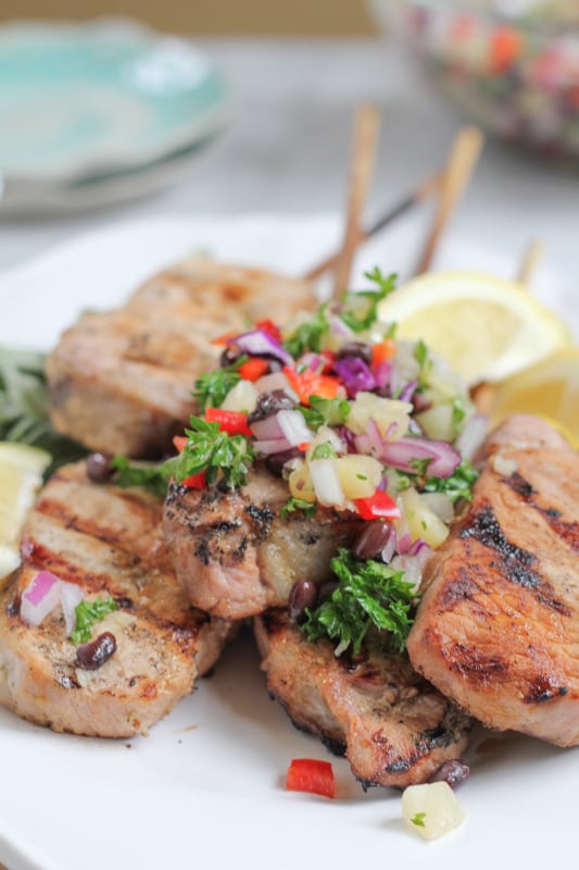 Grilled Pork Chops On a Stick With Pineapple Salsa on a plate.