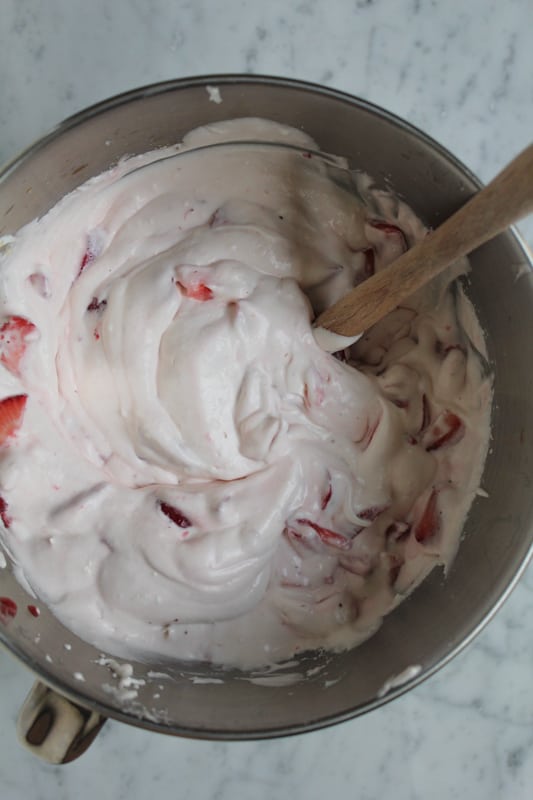 Strawberry Cheesecake Brownie Brittle Ice Cream being mixed in a bowl.