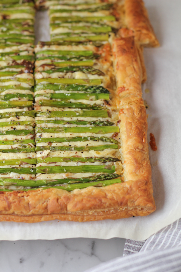 Sliced Asparagus Gruyere tart on parchment paper with a napkin.