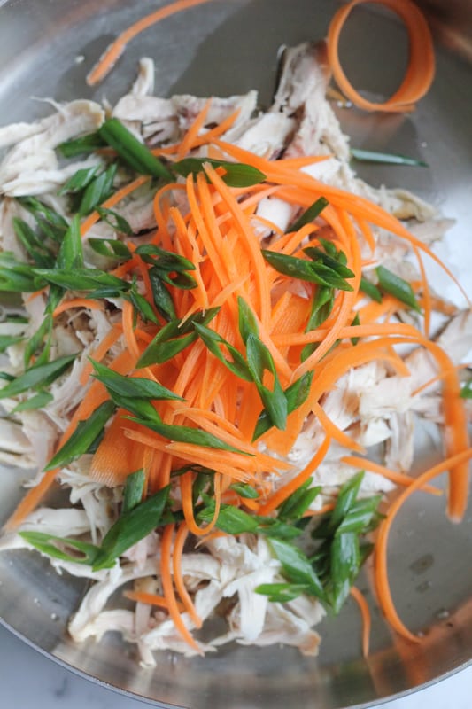 Chicken, carrots, and spring onions in a bowl for Chinese chicken salad.