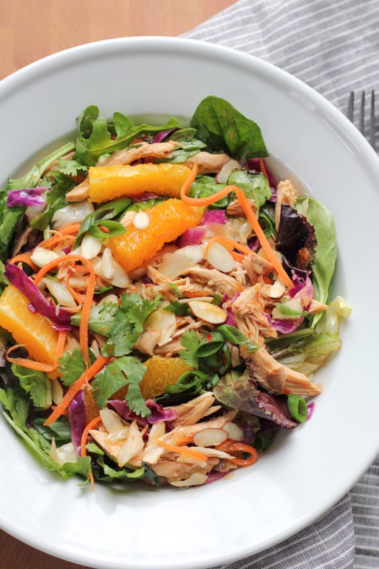 A bowl of Chinese chicken salad with a fork and napkin.