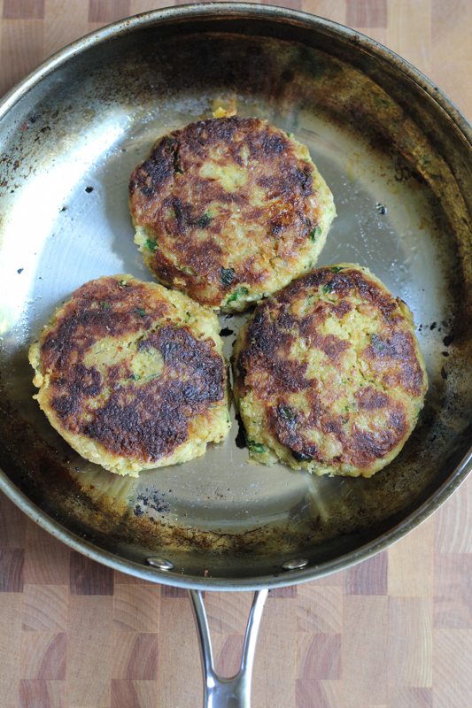 Three chickpea burgers in a skillet.