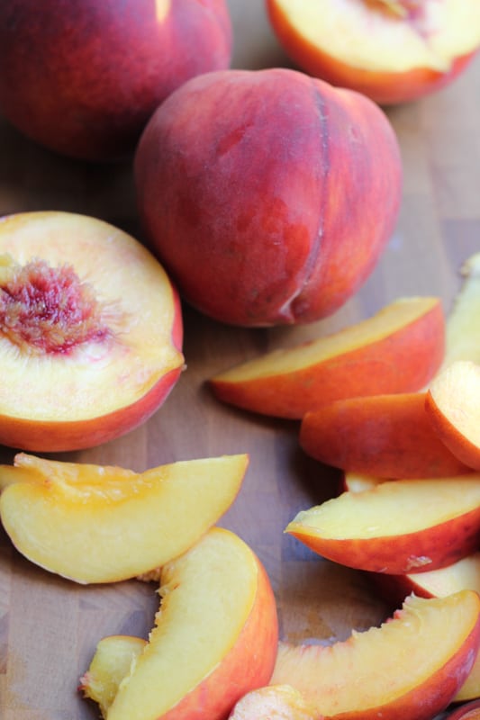 Peaches and slices of peaches for Olive Oil Honey Cake With Fresh Peaches.