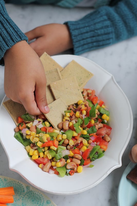 Crackers being dipped into a bowl of Texas Caviar.