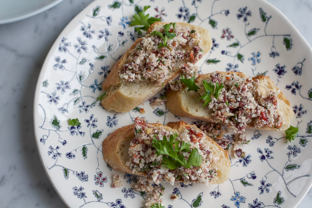Cauliflower Pesto Toasts! Incredibly easy to make and delicious! Bits of raw cauliflower with olives, sun dried tomatoes, garlic and more. These toasts are delicious!