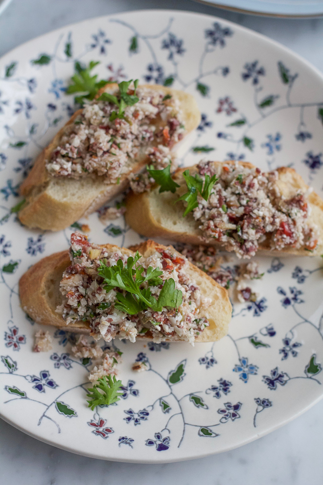 Cauliflower Pesto Toasts! Incredibly easy to make and delicious! Bits of raw cauliflower with olives, sun dried tomatoes, garlic and more. These toasts are delicious!