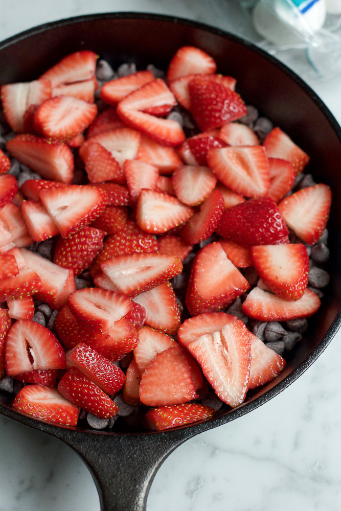Chocolate chips and strawberries in a cast iron skillet for Easy S'mores Dip.