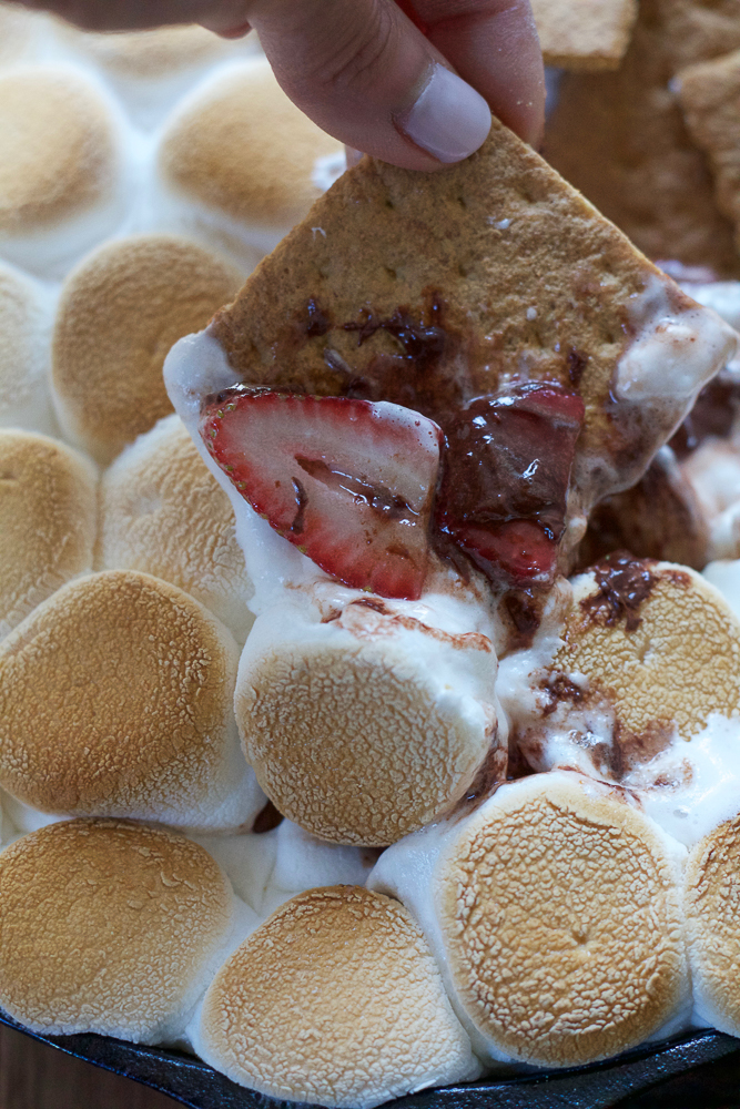 A graham cracker being dipped into Easy S'mores Dip.