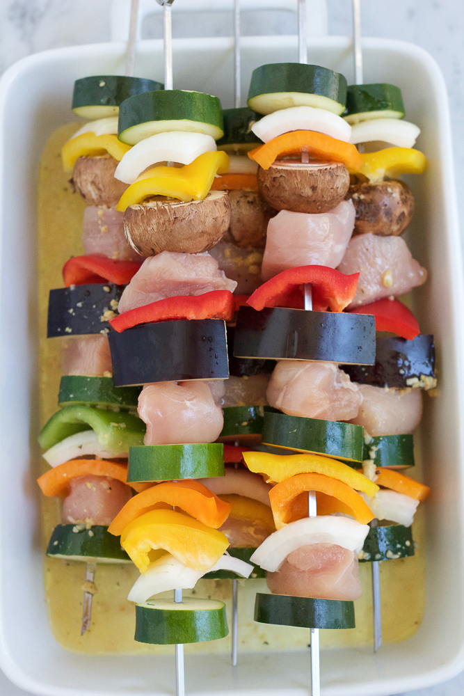 Uncooked Grilled Chicken Kebabs in a white baking dish.