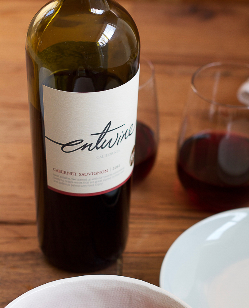 A bottle of wine, two wine glasses, and two white bowls.