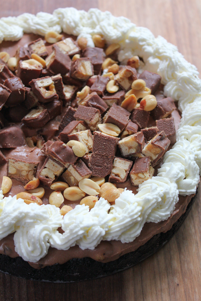 Hot Mess Nutella Snickers Pie!!! A creamy Nutella filling loaded with crushed peanuts and mini chocolate chips and topped with peanuts, whipped cream and bits of Snickers! This no bake pie is dessert heaven! From the cookbook, No-Bake Treats by Julianne Bayer.