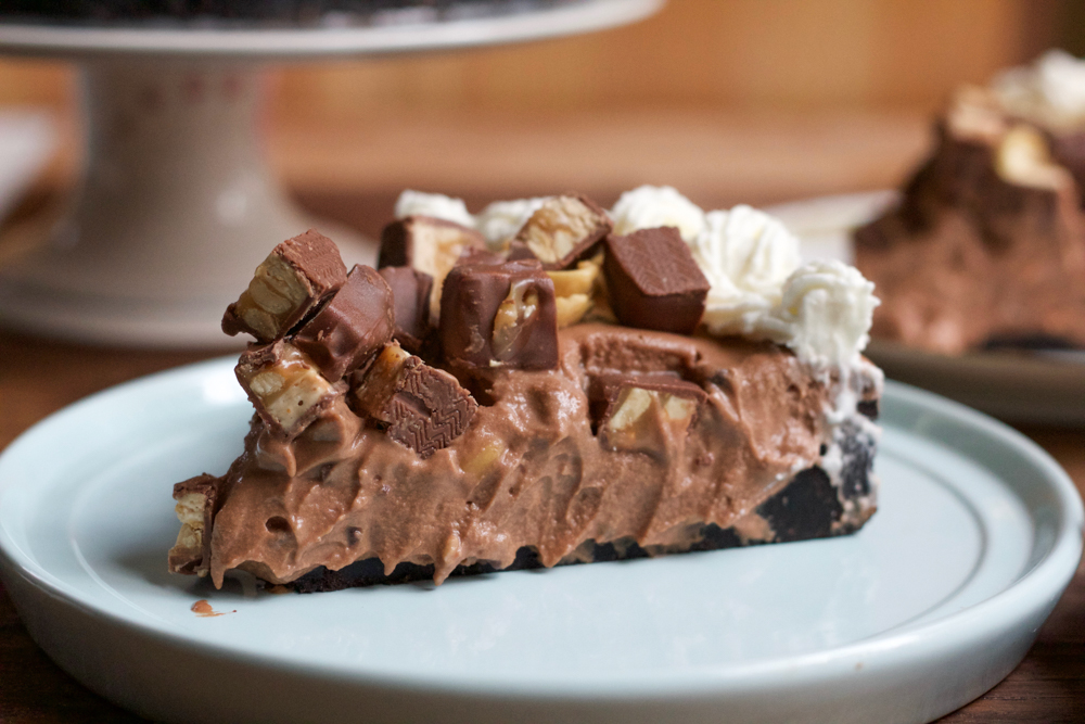 Hot Mess Nutella Snickers Pie!!! A creamy Nutella filling loaded with crushed peanuts and mini chocolate chips and topped with peanuts, whipped cream and bits of Snickers! This no bake pie is dessert heaven! From the cookbook, No-Bake Treats by Julianne Bayer.