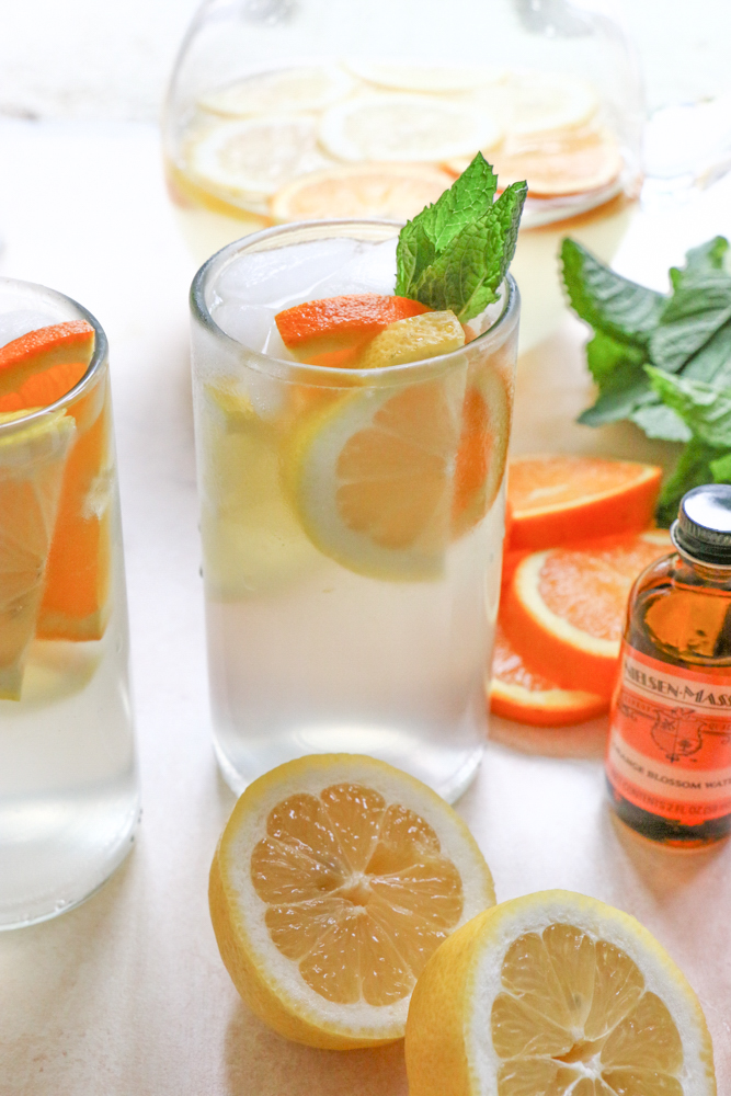 A glass of Orange Blossom Lemonade with oranges, lemons, mint, and orange blossom water.