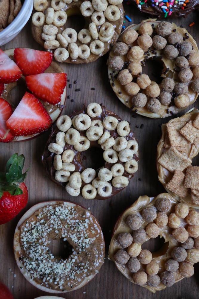 Cereal Apple Donuts! Fresh apple slices topped with peanut butter and almond butter and some of our favorite cereals from General Mills! The perfect summer snack!