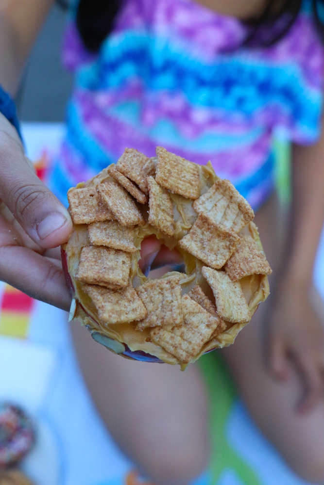 Cereal Apple Donuts! Fresh apple slices topped with peanut butter and almond butter and some of our favorite cereals from General Mills! The perfect summer snack!