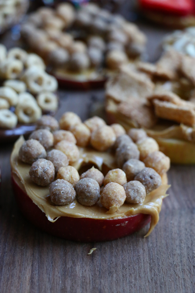 Cereal Apple Donuts! Fresh apple slices topped with peanut butter and almond butter and some of our favorite cereals from General Mills! The perfect summer snack!