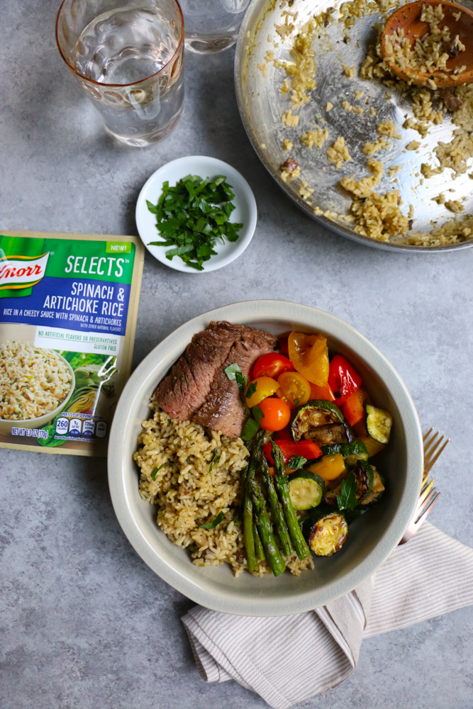 Summer Spinach Artichoke Rice Bowl with Vegetables with a package of spinach artichoke rice, forks and a napkin, and bowls of ingredients.
