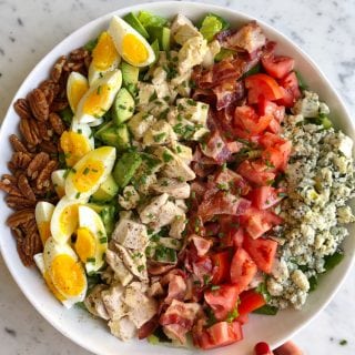 cobb salad ingredients layered in white bowl