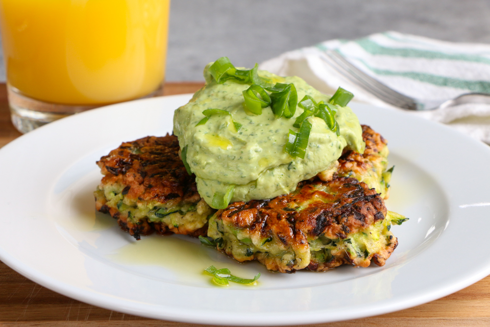 Zucchini Fritters with Avocado Crema!! It's all about brunch with a healthy twist! Savory and delicious and topped with a fresh avocado crema!